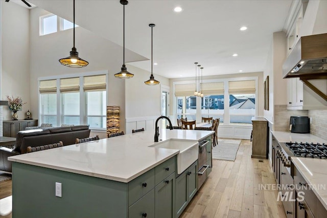 9351 W Sooty Grouse Ct, Boise, ID 83714 - kitchen with a sink, gas stovetop, light wood-type flooring, wall chimney exhaust hood, and tasteful backsplash