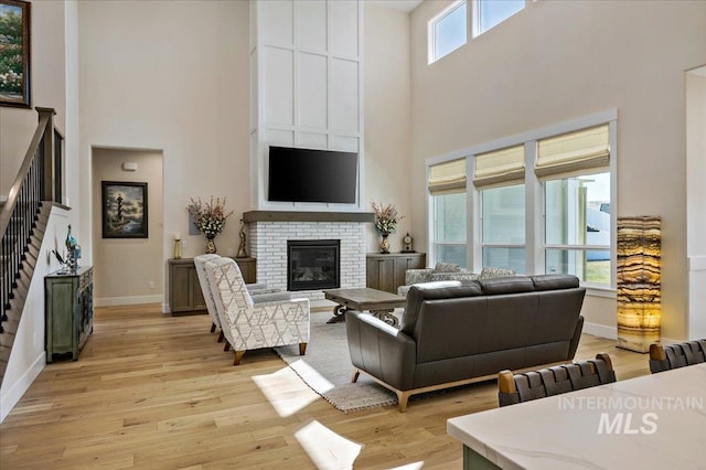 9351 W Sooty Grouse Ct, Boise, ID 83714 - living room with a high ceiling, light wood-style flooring, baseboards, stairs, and a brick fireplace