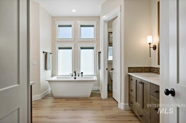 9351 W Sooty Grouse Ct, Boise, ID 83714 - bathroom with a freestanding bath, wood finished floors, vanity, decorative backsplash, and recessed lighting