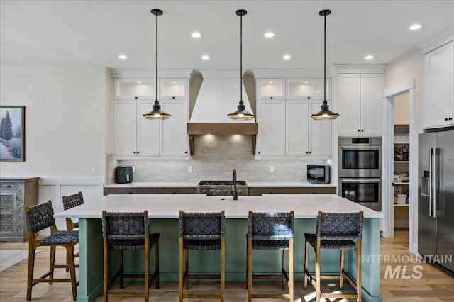 9351 W Sooty Grouse Ct, Boise, ID 83714 - kitchen with appliances with stainless steel finishes, premium range hood, white cabinetry, a sink, and decorative backsplash
