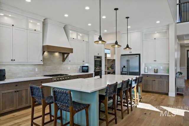 9351 W Sooty Grouse Ct, Boise, ID 83714 - kitchen featuring custom range hood, stainless steel appliances, decorative backsplash, a kitchen breakfast bar, and an island with sink