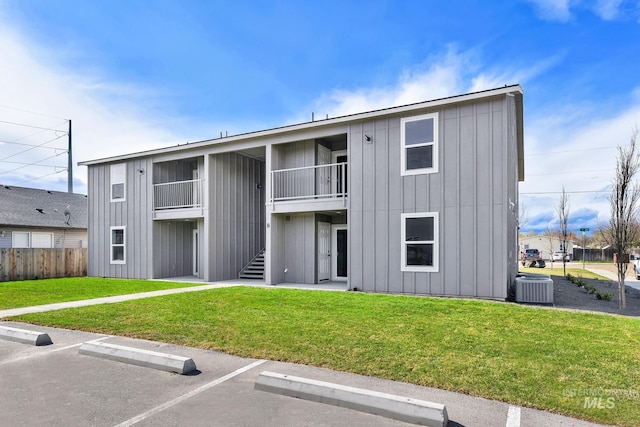 view of property featuring central AC unit, uncovered parking, and fence