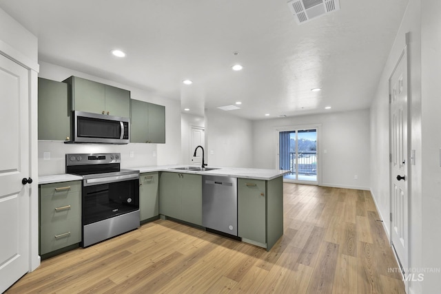kitchen with green cabinets, a sink, visible vents, a peninsula, and appliances with stainless steel finishes