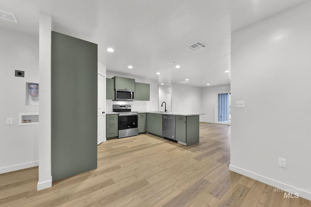 kitchen featuring green cabinets, light wood-style flooring, visible vents, a peninsula, and appliances with stainless steel finishes