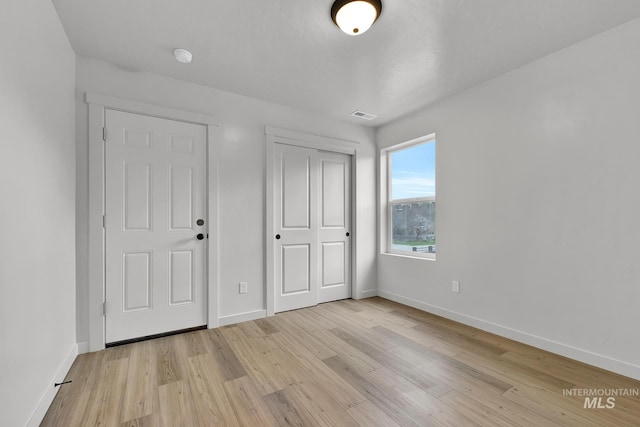 unfurnished bedroom featuring light wood finished floors, baseboards, and visible vents