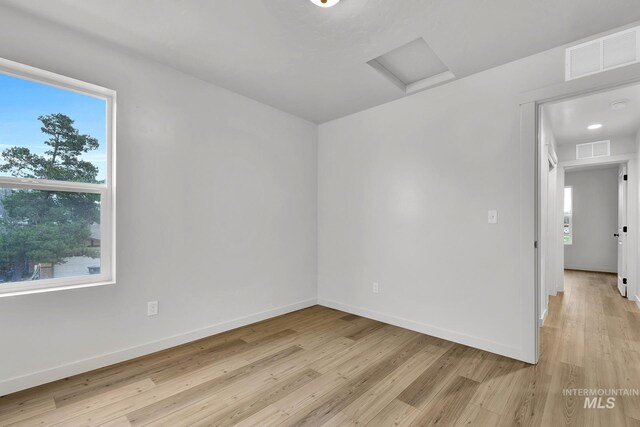 spare room with light wood-type flooring, attic access, and visible vents