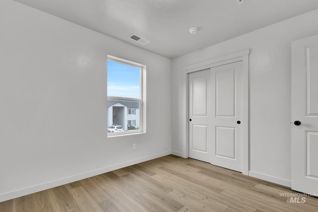 unfurnished bedroom with baseboards, visible vents, light wood-style flooring, and a closet