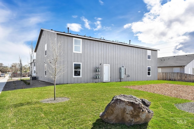back of property with fence, board and batten siding, and a yard