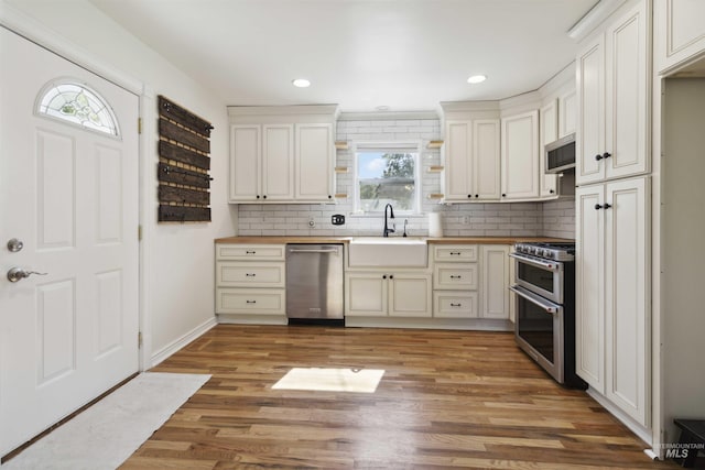 608 S Eagleson Rd, Boise, ID 83705 - kitchen featuring stainless steel appliances, a sink, butcher block counters, decorative backsplash, and recessed lighting