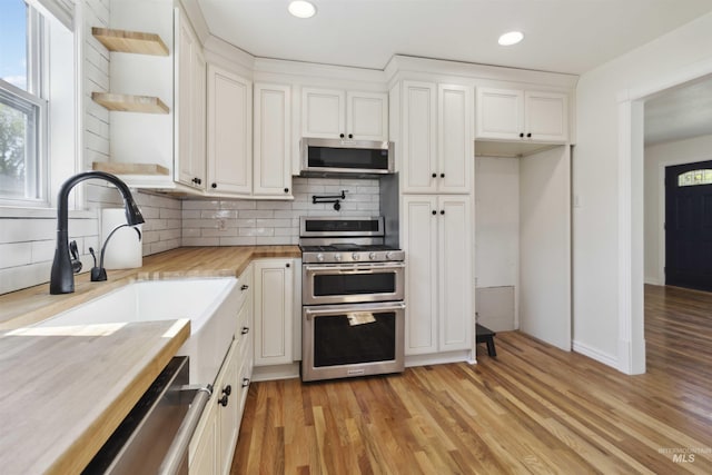 608 S Eagleson Rd, Boise, ID 83705 - kitchen featuring appliances with stainless steel finishes, open shelves, wooden counters, light wood-style flooring, and decorative backsplash