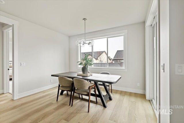 dining area with a notable chandelier, light wood-style flooring, and baseboards