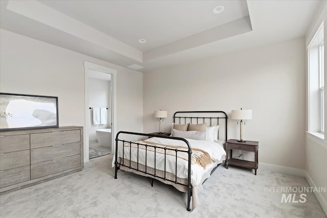 bedroom featuring baseboards, a raised ceiling, carpet floors, and ensuite bath