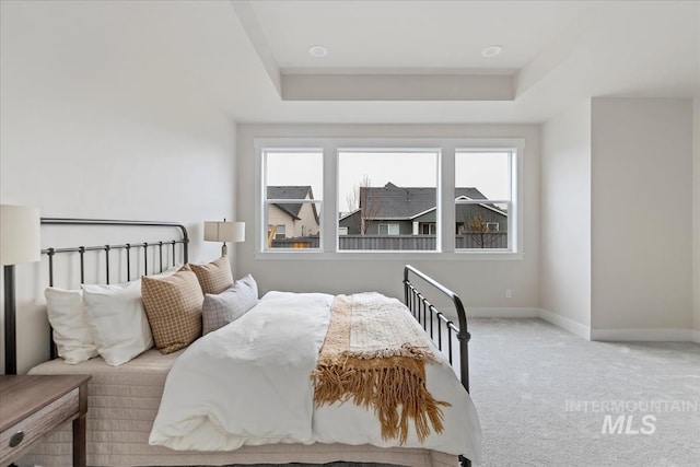 bedroom featuring a raised ceiling, carpet, and baseboards