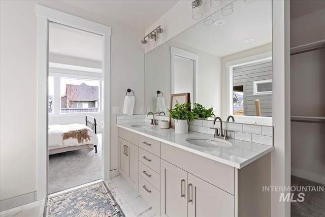 bathroom featuring double vanity, connected bathroom, marble finish floor, and a sink