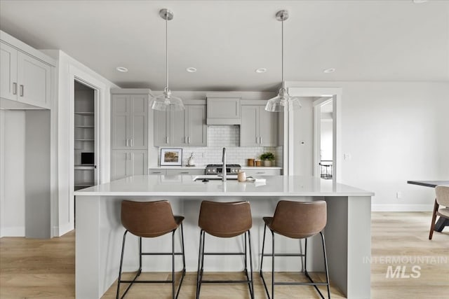 kitchen with light countertops, light wood-style flooring, a breakfast bar area, and backsplash