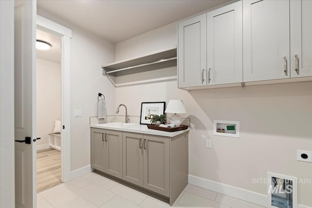 laundry room featuring hookup for a washing machine, baseboards, hookup for an electric dryer, cabinet space, and a sink