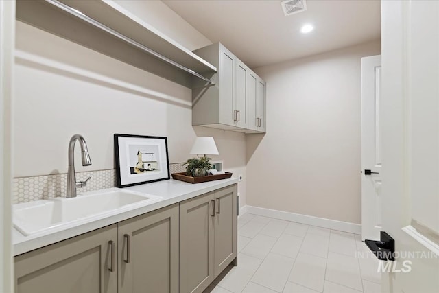 laundry room featuring hookup for a washing machine, baseboards, visible vents, cabinet space, and a sink