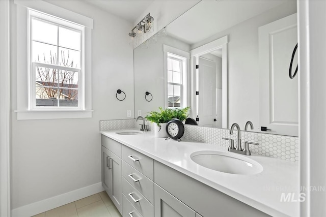 bathroom with double vanity, tile patterned floors, baseboards, and a sink