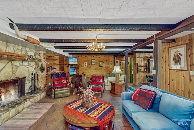 living room featuring wooden walls, an inviting chandelier, a fireplace, and beamed ceiling