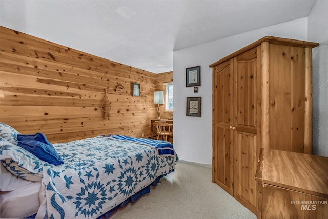 bedroom featuring wood walls and light carpet