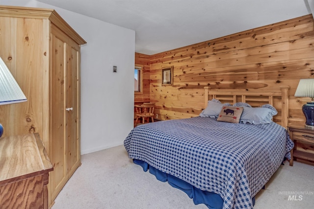 bedroom with light colored carpet and wood walls