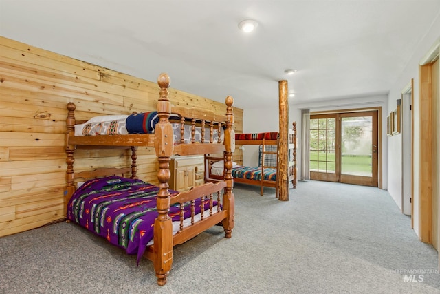 carpeted bedroom with wood walls and access to outside