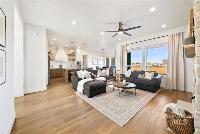 living area with light wood-style floors, baseboards, a ceiling fan, and recessed lighting