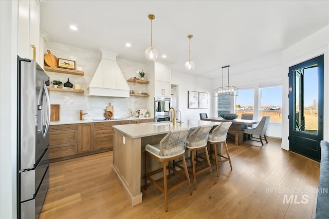 kitchen with stainless steel appliances, premium range hood, light countertops, and open shelves