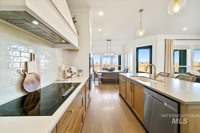 kitchen with custom range hood, black electric stovetop, light wood-style flooring, dishwasher, and a sink