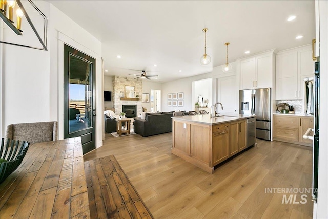 kitchen featuring open floor plan, ceiling fan, light wood-style floors, and stainless steel appliances