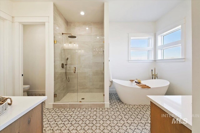 bathroom featuring a shower stall, a freestanding tub, vanity, and toilet
