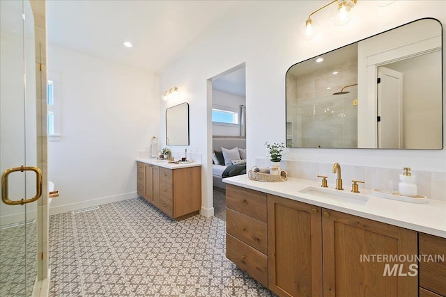ensuite bathroom with two vanities, a sink, a stall shower, baseboards, and tile patterned floors