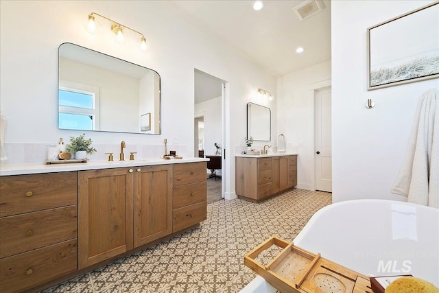 full bathroom with two vanities, visible vents, recessed lighting, a sink, and a freestanding bath