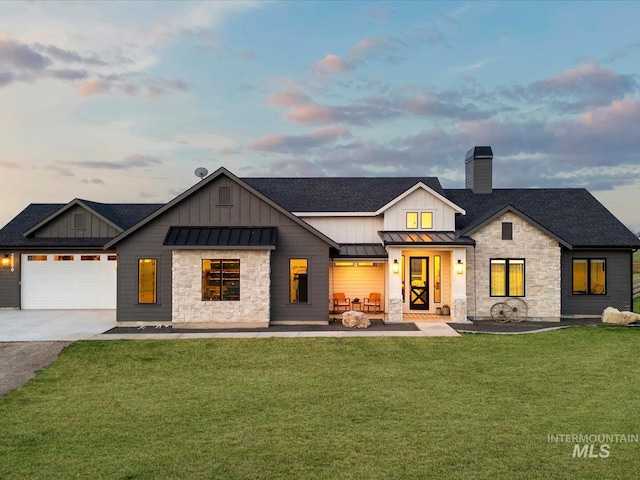 modern farmhouse featuring a yard, a standing seam roof, stone siding, and a chimney