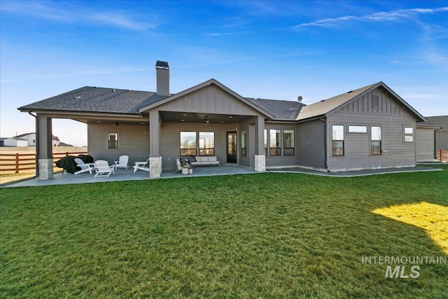 rear view of property with a patio area, fence, a yard, and board and batten siding