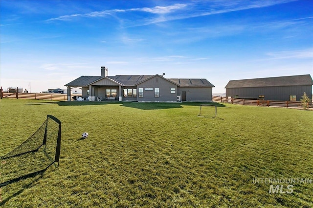 rear view of house featuring an outbuilding, a yard, fence, and a chimney