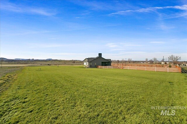 view of yard with a rural view, fence, and an outbuilding