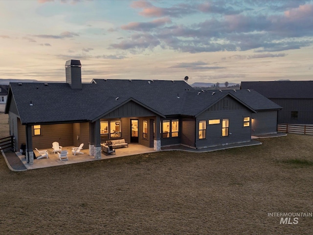 rear view of house featuring a patio area, fence, a shingled roof, and board and batten siding