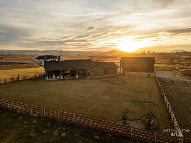 back of house with a rural view, fence, and an outdoor structure