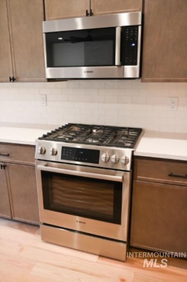 kitchen featuring appliances with stainless steel finishes, tasteful backsplash, and light wood-type flooring