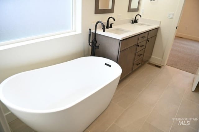 bathroom featuring a bathing tub, vanity, and tile patterned floors