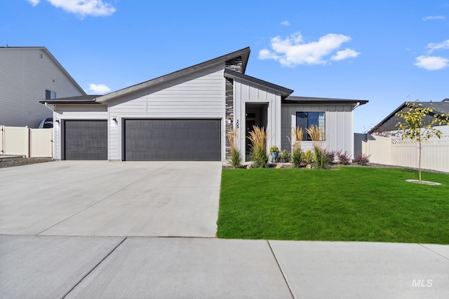 view of front facade featuring driveway, fence, board and batten siding, a front yard, and a garage