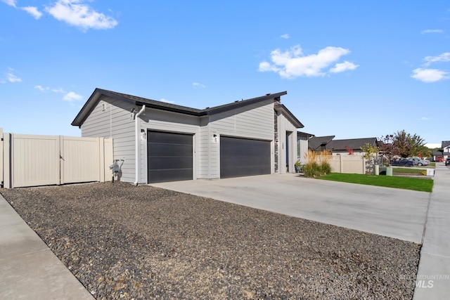 view of property exterior with concrete driveway, a gate, fence, and a garage