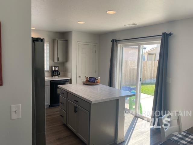 kitchen featuring gray cabinets, black dishwasher, a center island, and hardwood / wood-style floors