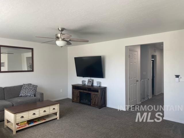 living room featuring ceiling fan and dark colored carpet