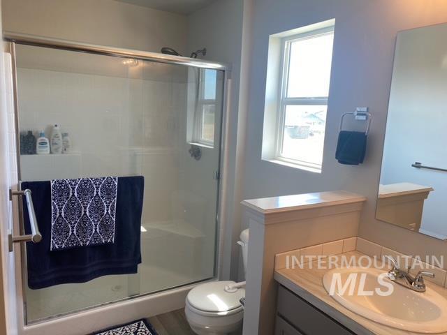 bathroom with toilet, an enclosed shower, and vanity