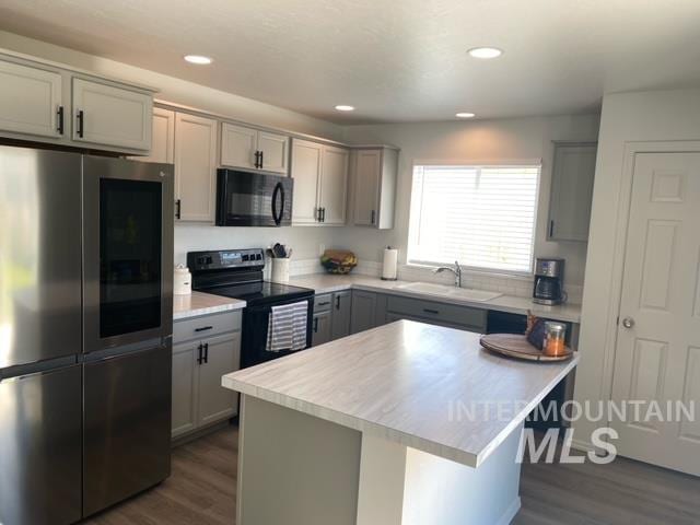 kitchen with sink, black appliances, gray cabinetry, and a center island