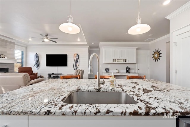 kitchen with light stone counters, decorative light fixtures, and crown molding