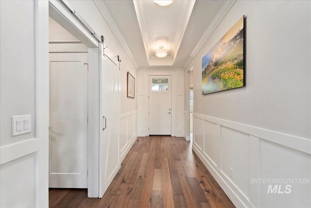 doorway to outside featuring dark hardwood / wood-style floors, ornamental molding, a barn door, and a tray ceiling