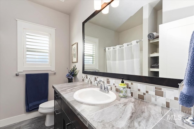 bathroom featuring vanity, hardwood / wood-style flooring, tasteful backsplash, and toilet